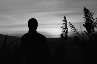 Silhouette man standing on field against sky during sunset