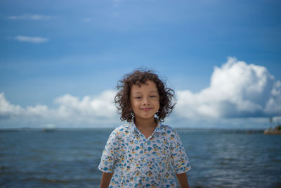 Portrait of a boy standing against sea against sky