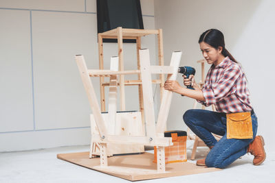 Young woman photographing while sitting on wall at home