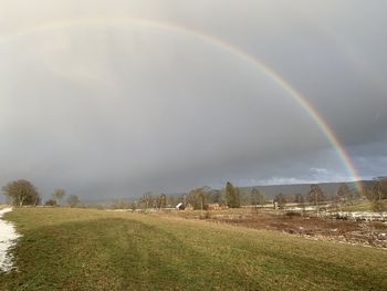 Scenic view of rainbow over field against sky