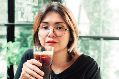 Portrait of young woman holding drink in cafe