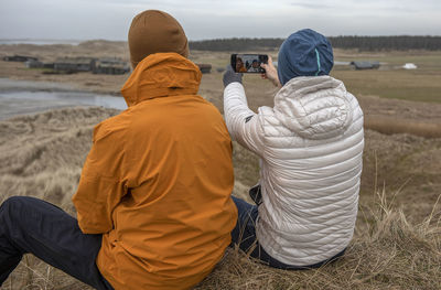 Rear view of man photographing woman using smart phone