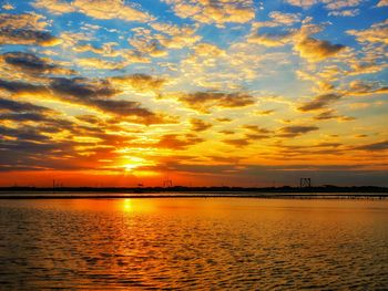 Scenic view of sea against dramatic sky during sunset