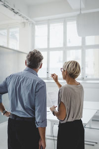 Rear view of mature businessman and businesswoman discussing in new office