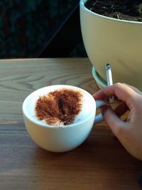 Close-up of hand holding coffee cup on table