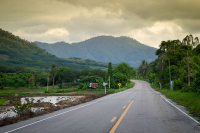 Road leading towards mountains against sky