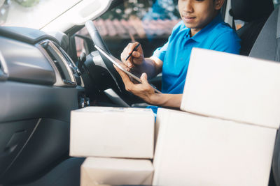 Delivery man using digital tablet while sitting in car