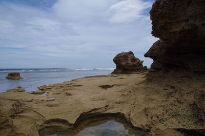 Rock formation on beach against sky