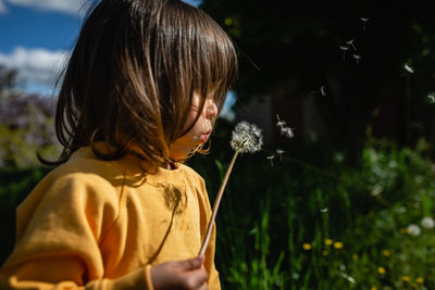 Child blowing a dandelion