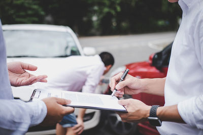 Midsection of couple holding hands in car