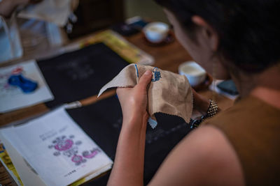 Midsection of woman making embroidery on fabric