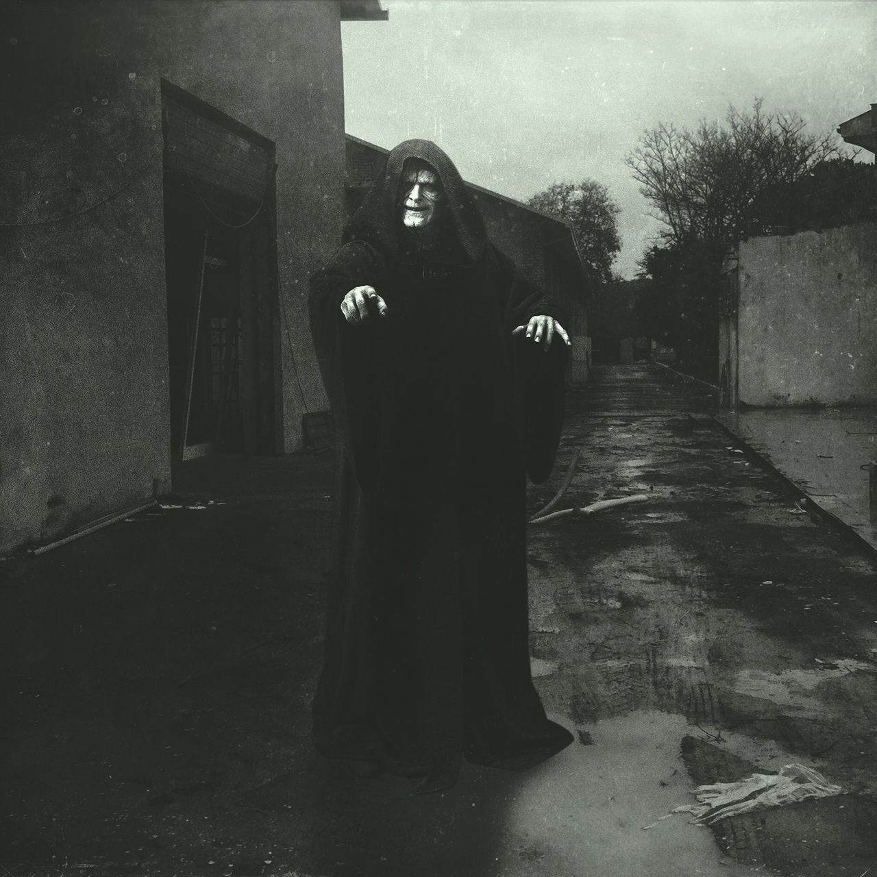 PORTRAIT OF WOMAN STANDING ON FOOTPATH AMIDST BUILDING