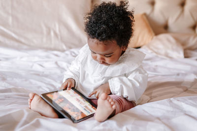 Mixed race african black toddler baby girl watching cartoons on tablet. ethnic diversity. 