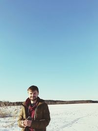 Portrait of smiling young man standing in snow