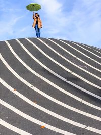 Woman standing by umbrella against sky