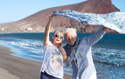 Senior couple holding scarf at beach
