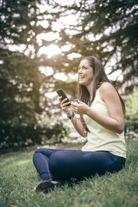 Smiling woman listening music while sitting in park