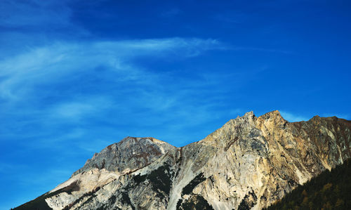 Low angle view of rocky mountains against blue sky