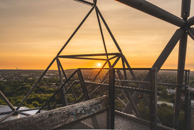 Metal fence against orange sky