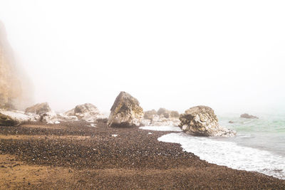 Rocks on beach against clear sky