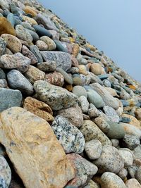 Close-up of pebbles on beach against clear sky