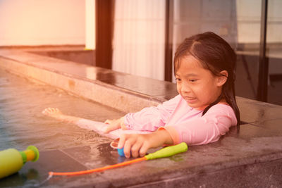Girl plays water near poolside in swimming with sun light in summer vacation time