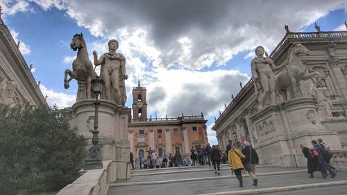 Statue in city against cloudy sky