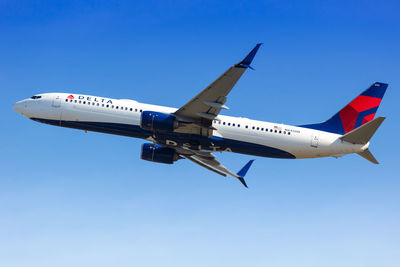 Low angle view of airplane against clear blue sky