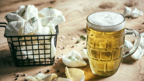 Draught beer with potato chips with dill and condiments on wooden table pub drink and food