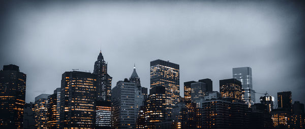 Illuminated buildings against sky at dusk