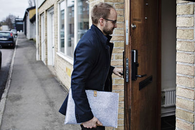 Side view of male owner entering eyeglasses workshop