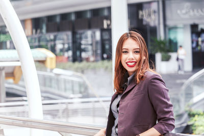 Portrait of smiling young businesswoman standing on elevated walkway 