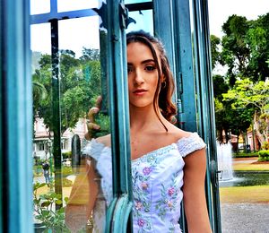 Portrait of beautiful woman standing by window