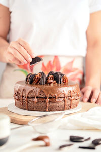 Midsection of woman with chocolate cake on table