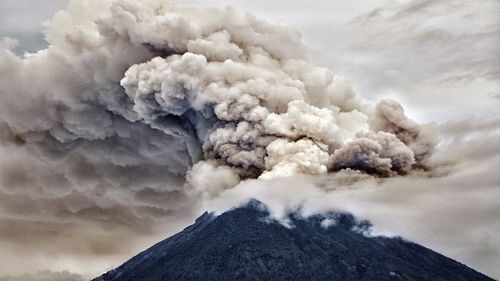 Smoke emitting from volcanic mountain against sky