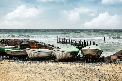 Boats moored on shore at beach against sky