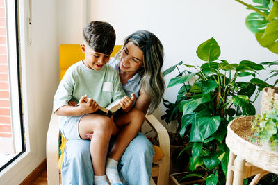 Young family mother and son reading a book in sofa at home