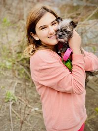 Portrait of smiling girl holding puppy while standing outdoors