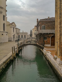 Bridge over canal amidst buildings in city against sky