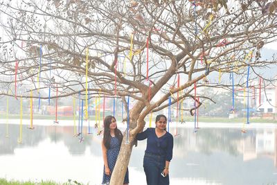 Young women standing by tree