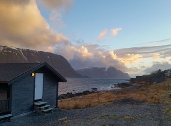 House by sea against sky during sunset