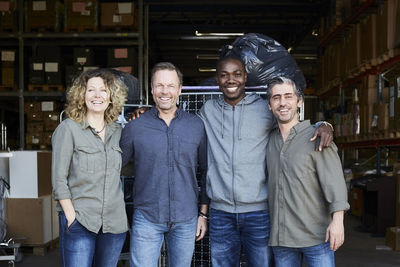 Portrait of smiling colleagues standing at warehouse doorway