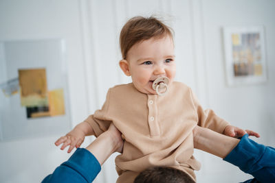 Joyful child with a pacifier in his father's arms