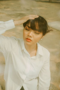 Young woman with eyes closed sitting outdoors