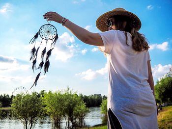 Rear view of woman holding umbrella against sky