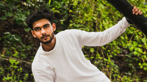 Portrait of young man standing against plants