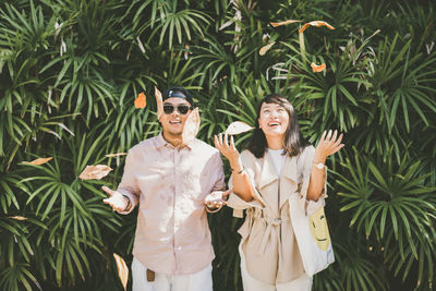 Cheerful young couple standing against plants