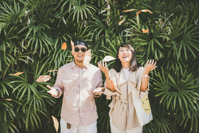 Portrait of young couple standing against plants