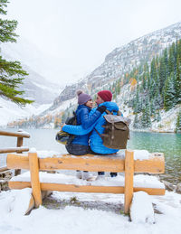 Couple sitting on snow covered mountain