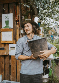 Smiling male volunteer with container looking away in urban farm